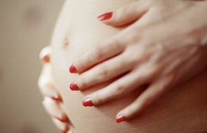 close-up of a woman holding her pregnant stomach